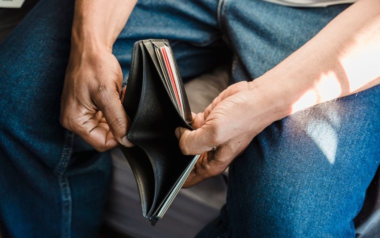 Close-up of a man holding an empty wallet, symbolizing financial crisis and hardship. Gros plan d'un homme tenant un portefeuille vide, symbolisant une crise financière et des difficultés.