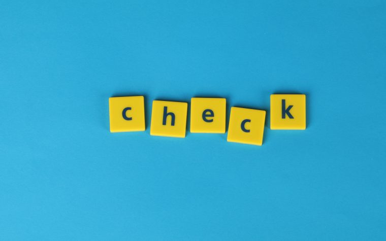 Yellow letter tiles spelling 'check' on a vibrant blue background, conveying approval or verification. Des tuiles de lettres jaunes formant le mot "check" sur un fond bleu vibrant, véhiculant l'approbation ou la vérification.