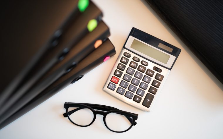 Calculator with glasses and folders on an office desk. Perfect for finance and accounting themes. Calculatrice avec lunettes et dossiers sur un bureau. Parfait pour les thèmes de finance et de comptabilité.