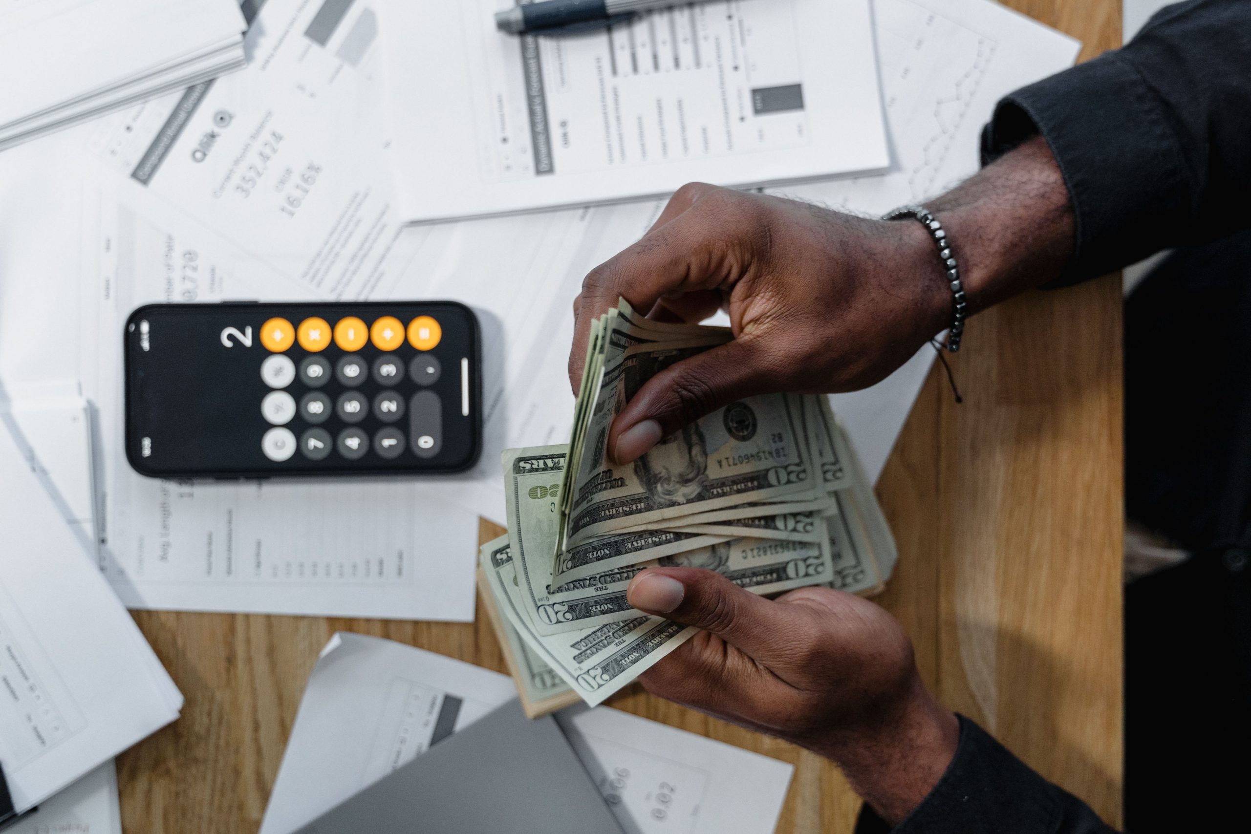 Personne comptant des billets avec calculatrice smartphone