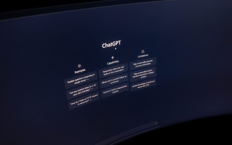 Close-up of a computer screen displaying ChatGPT interface in a dark setting. Gros plan d'un écran d'ordinateur affichant l'interface ChatGPT dans un environnement sombre.