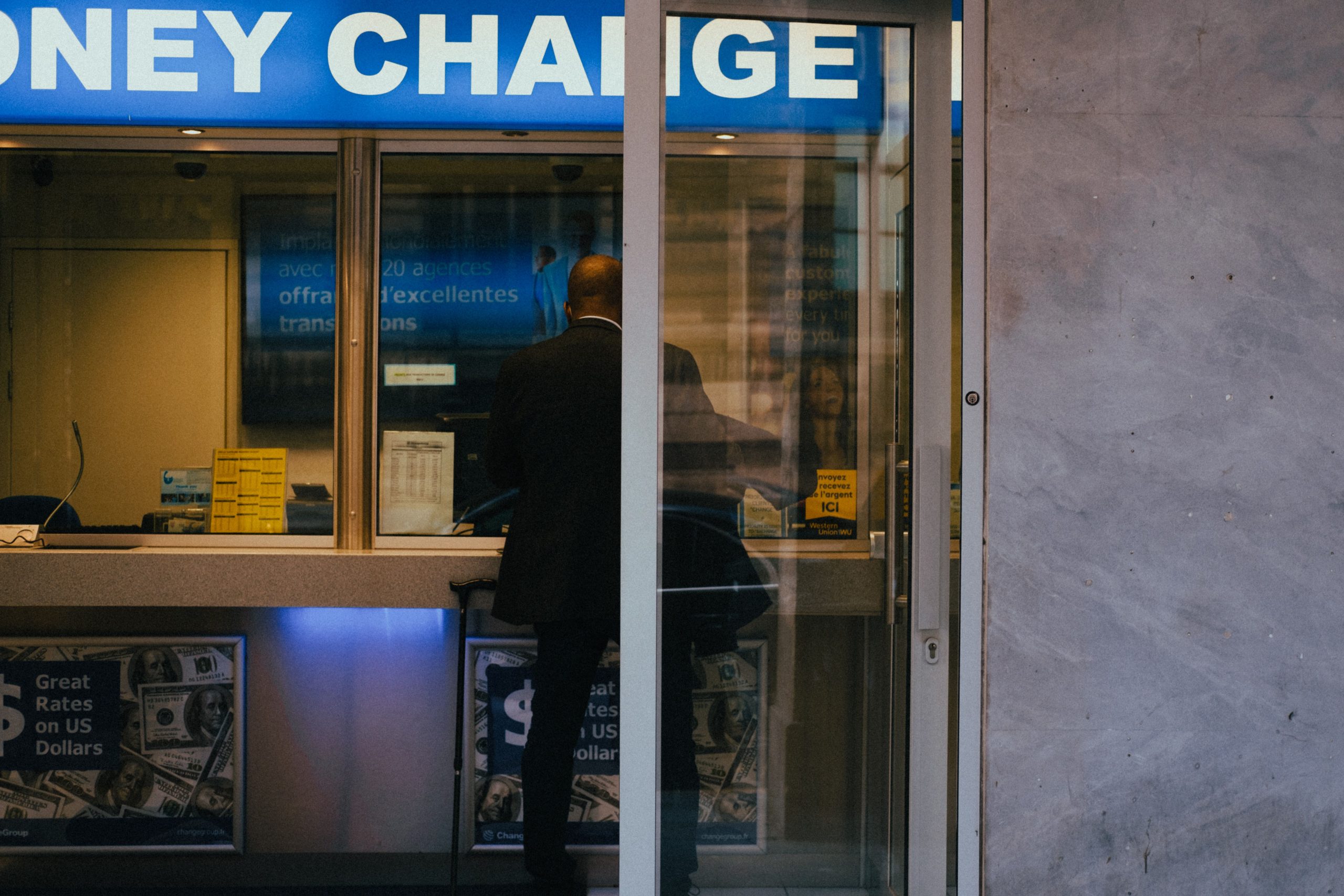 Homme à un guichet de change affichant les taux