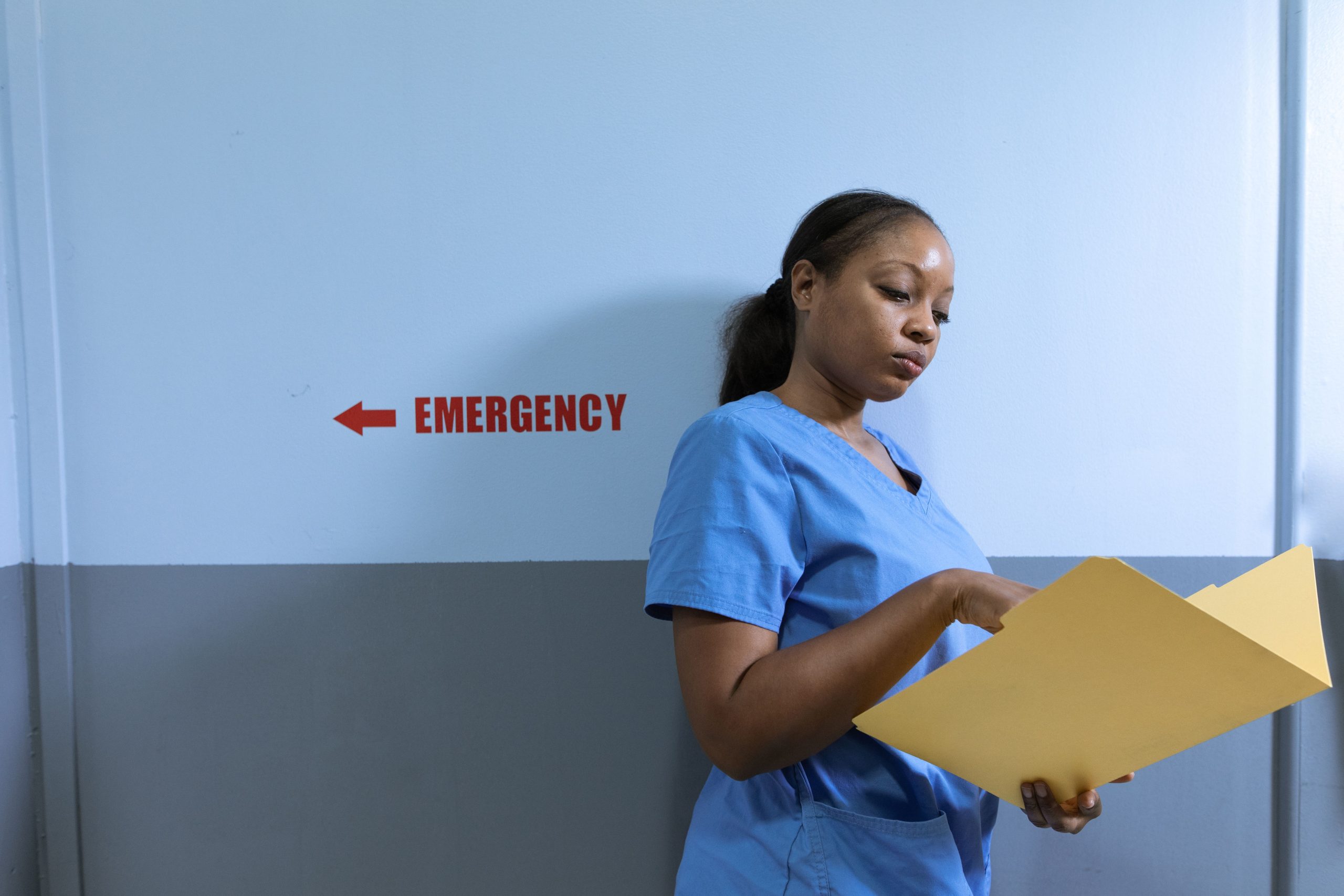 Infirmière en blouse bleue lisant dossier médical