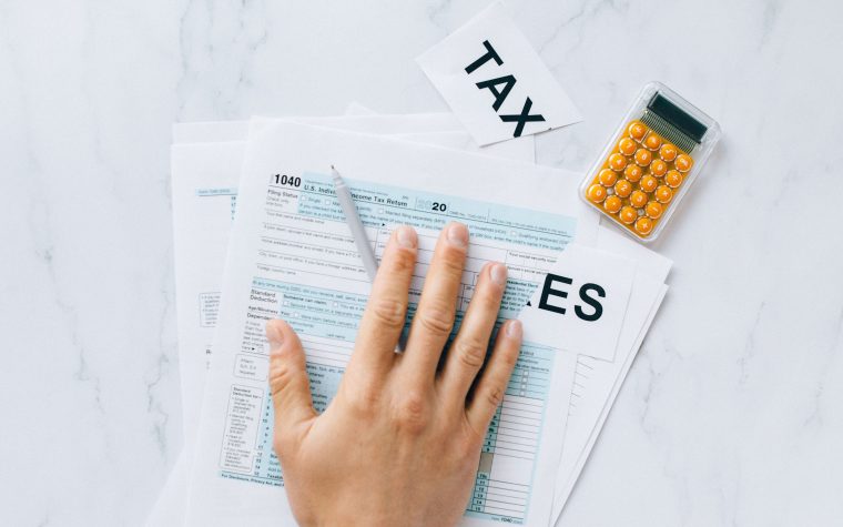Main remplissant un formulaire fiscal avec calculatrice